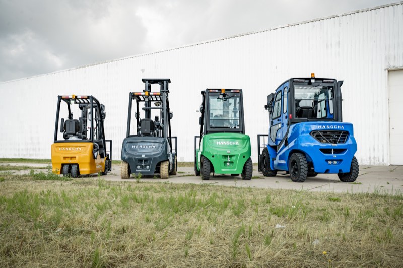 Vier Hangcha heftrucks in geel, grijs, groen en blauw naast elkaar op het gras