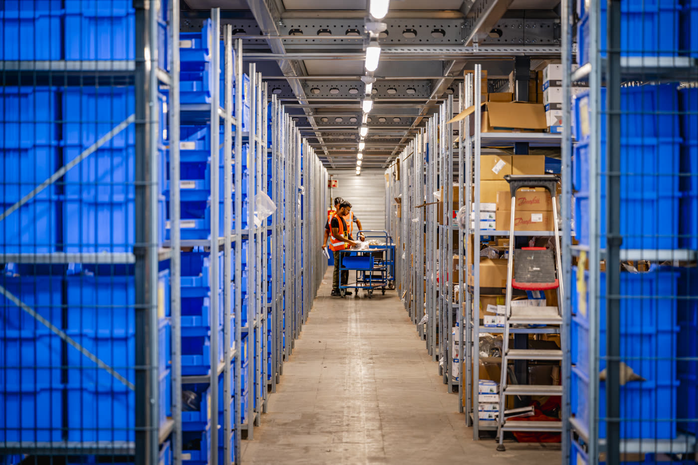 Magazijnmedewerker tussen hoge stellingen met blauwe onderdelenbakken in het Hangcha magazijn in Almere