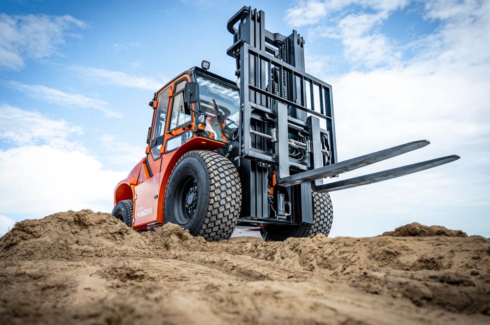 Oranje elektrische Hangcha RT ruwterreinheftruck met Li-ion aandrijving op een zandheuvel tegen een blauwe lucht