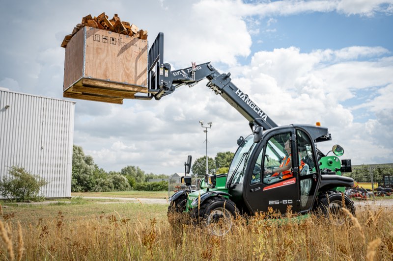 Groene Hangcha verreiker tilt een kist met blokken hout omhoog in het veld